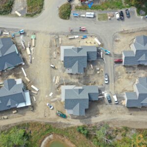 A top-down view of six houses being built in the Piper Shores development. The worksite is under construction with many piles of construction equipment and vehicles scattered throughout.
