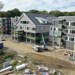 A large building under construction at the Pipers Shores community. The building has many windows and balconies that are being built. There are construction vehicles and materials throughout the worksite.